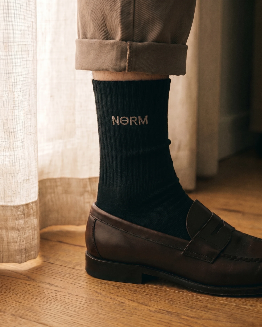 NƟRM Everyday Crew in black, worn mid-calf, ribbed cuff and reinforced heel visible.