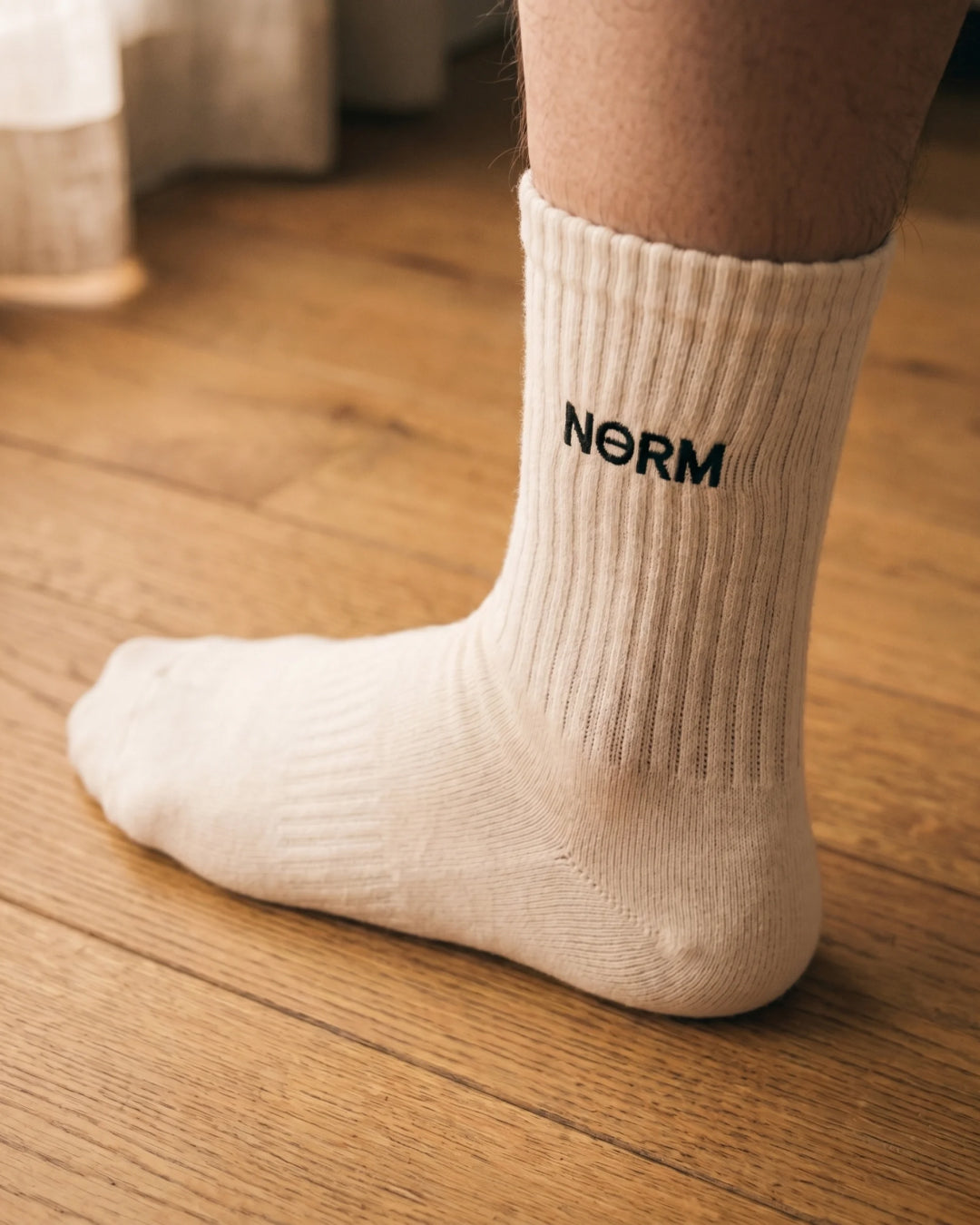 NƟRM Everyday Crew white, angled on foot, reinforced heel visible, mid-calf shot.