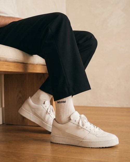 NƟRM Everyday Crew in white, worn mid-calf, ribbed cuff and reinforced heel visible.